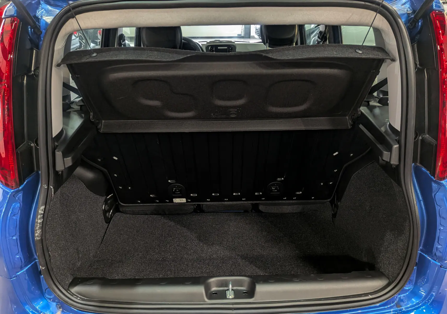 Coffre ouvert vu de l'arrière d'une Fiat Panda 1.0 Hybrid City 2025 en Bleu Italia, montrant l'espace de chargement vide.