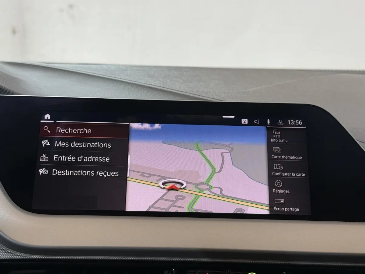 Écran tactile central de navigation affichant une carte, dans l’habitacle beige d’une BMW Série 1 noire.