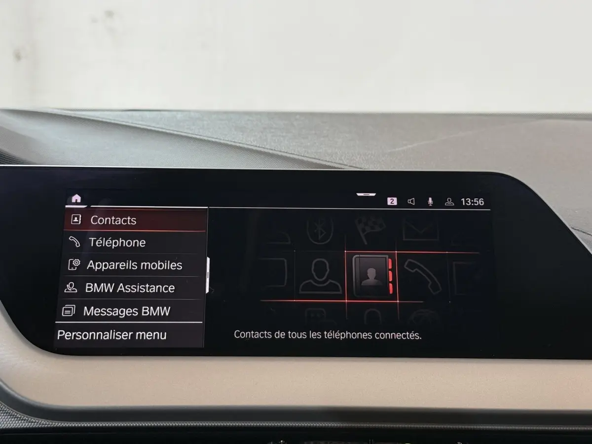 Écran tactile central de la BMW Série 1 116d Business Design 2022 affichant le menu contacts en intérieur noir et beige.