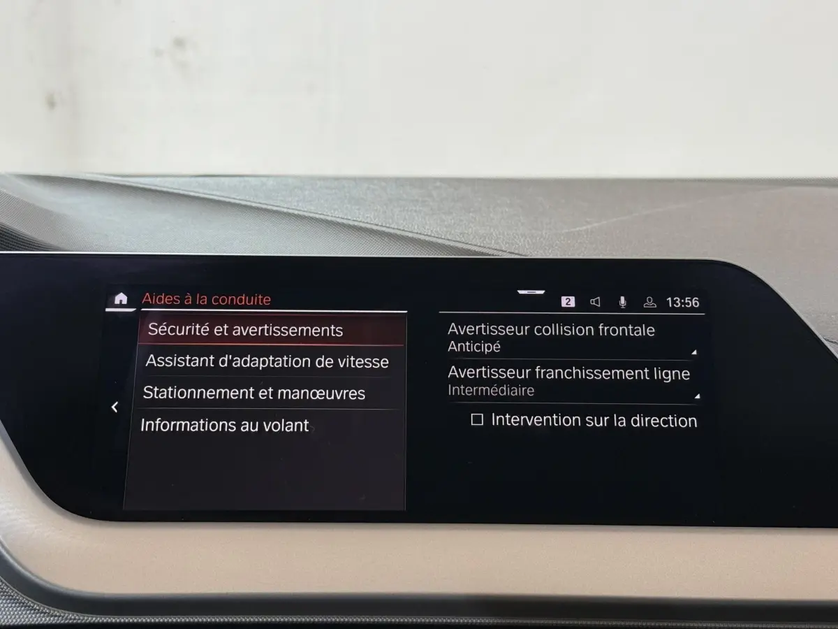 Écran tactile central de la BMW Série 1 116d Business Design affichant les aides à la conduite, intérieur beige.