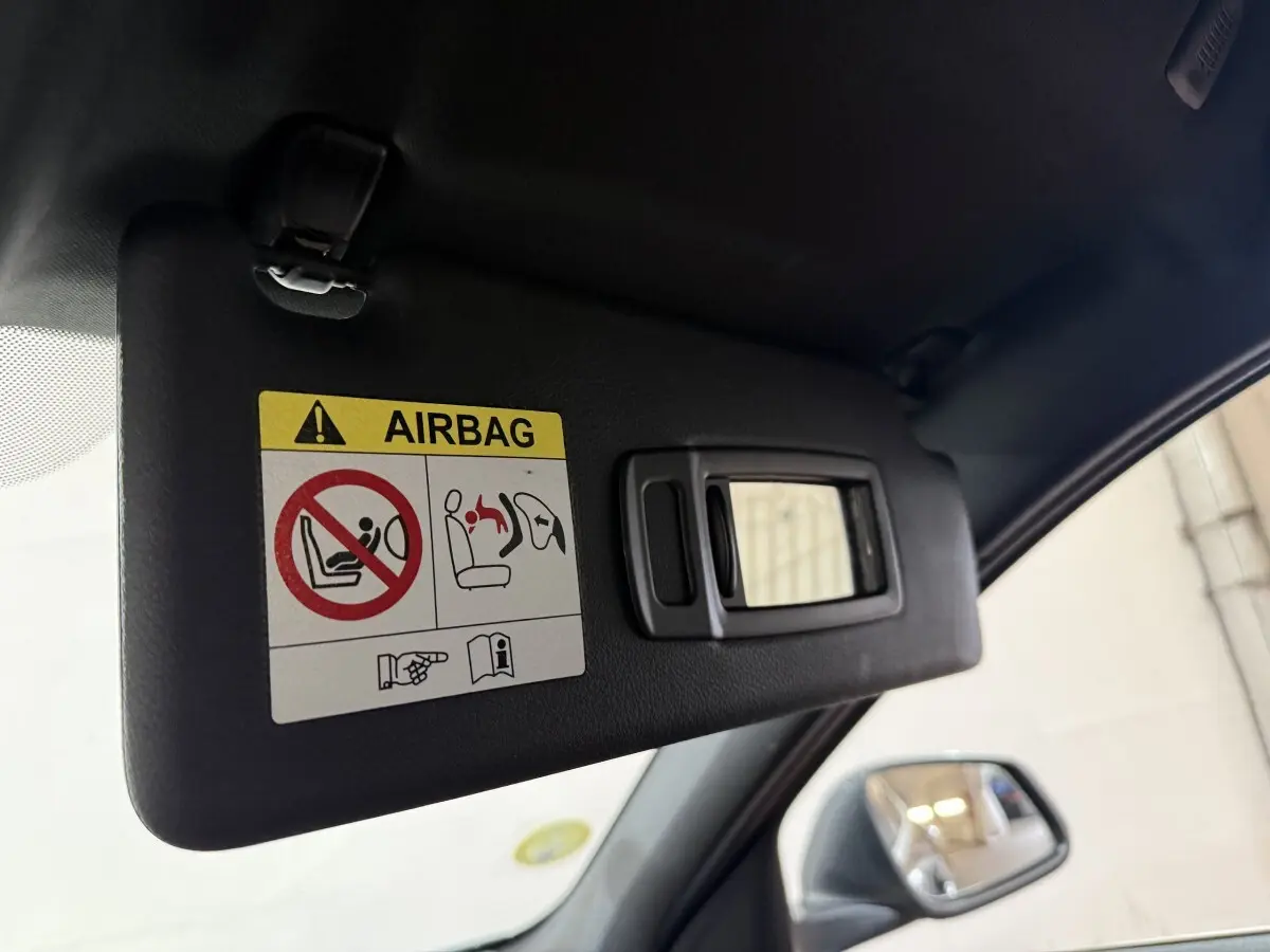 Détail du pare-soleil côté conducteur avec miroir et avertissement airbag dans BMW Série 1 noir 116d 2022.