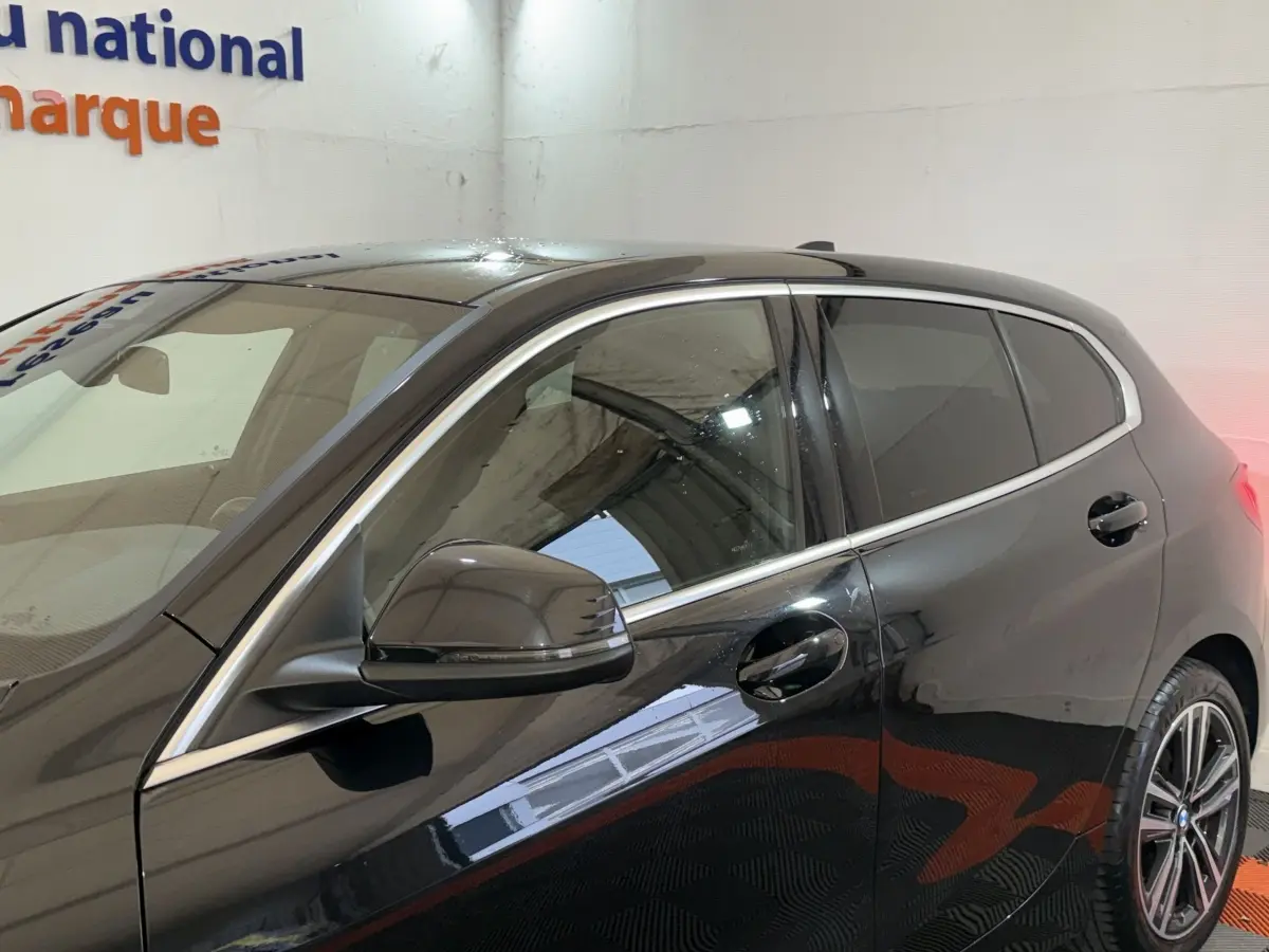 Vue latérale gauche rapprochée d’une BMW Série 1 116d noire mettant en valeur les contours chromés et la jante alliage.