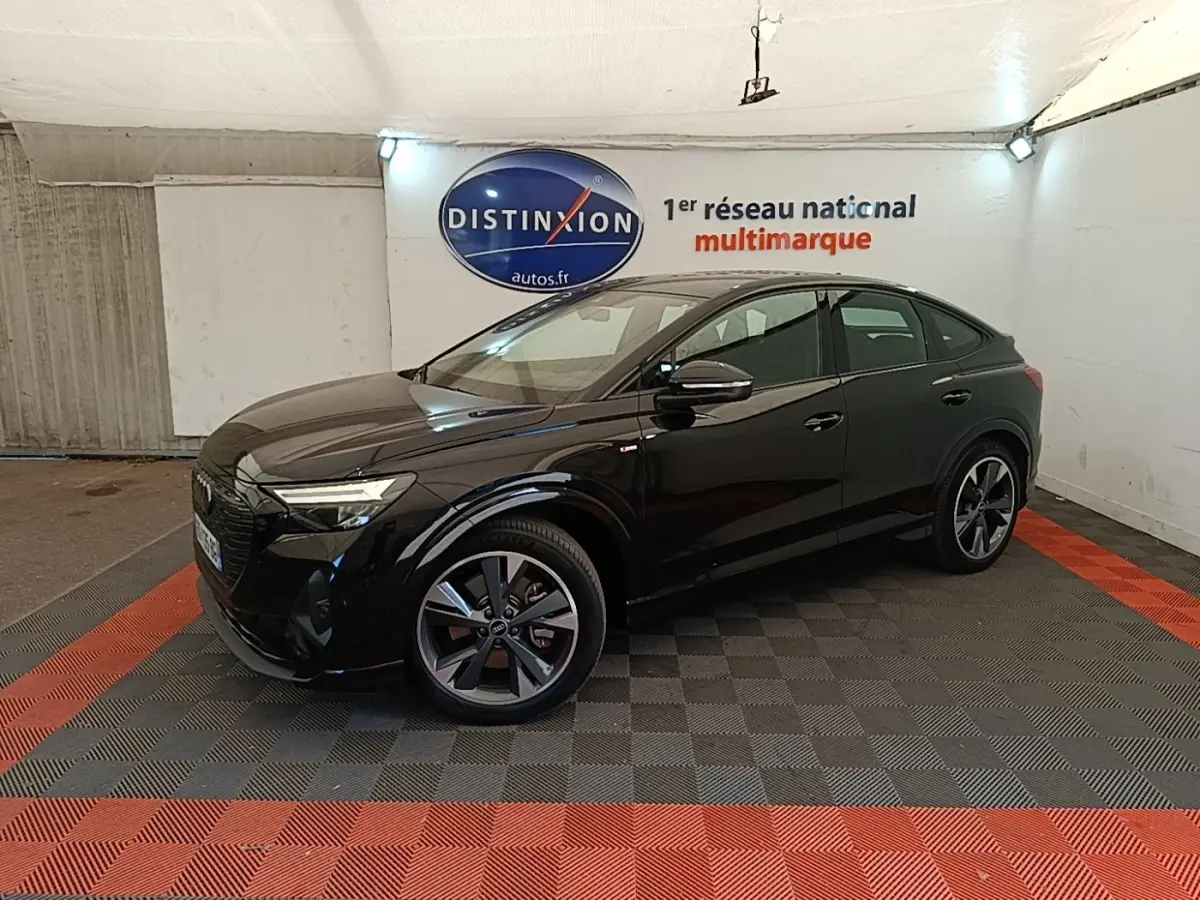 Audi Q4 E-Tron Sportback noir vue 3/4 avant droit en intérieur avec jantes S Line distinctives.