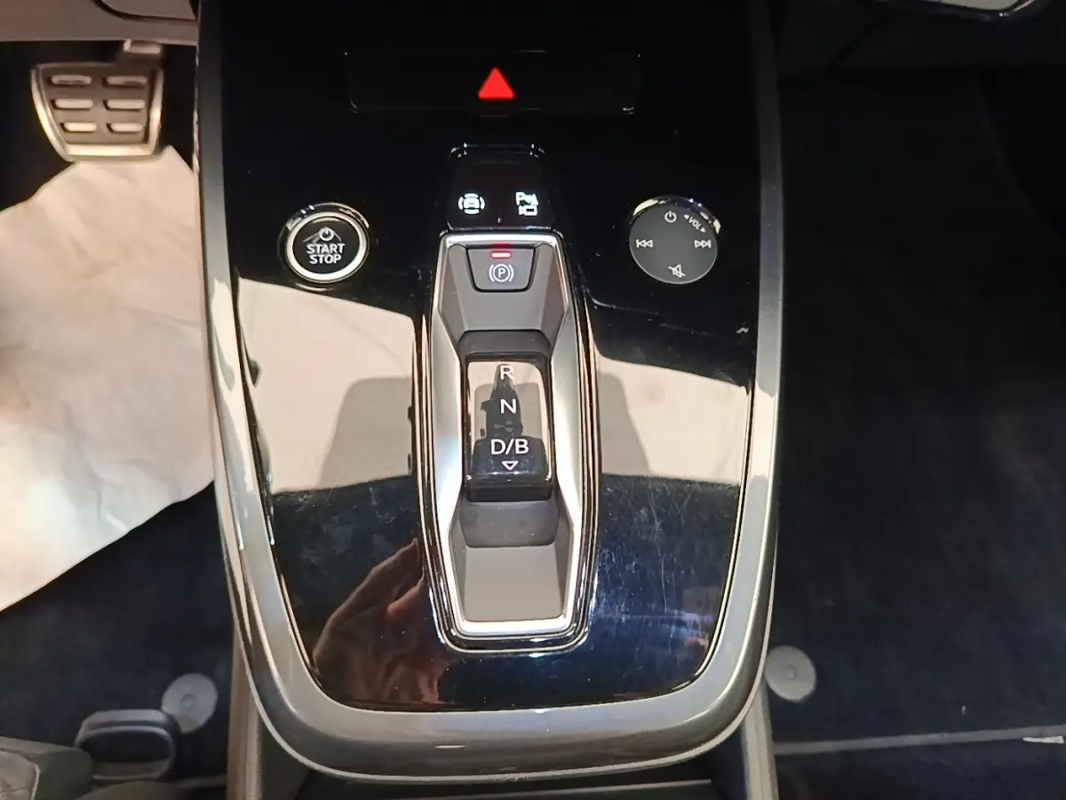 Gros plan sur la console centrale noire de l’Audi Q4 E-TRON Sportback avec levier de vitesses automatique et bouton start/stop.