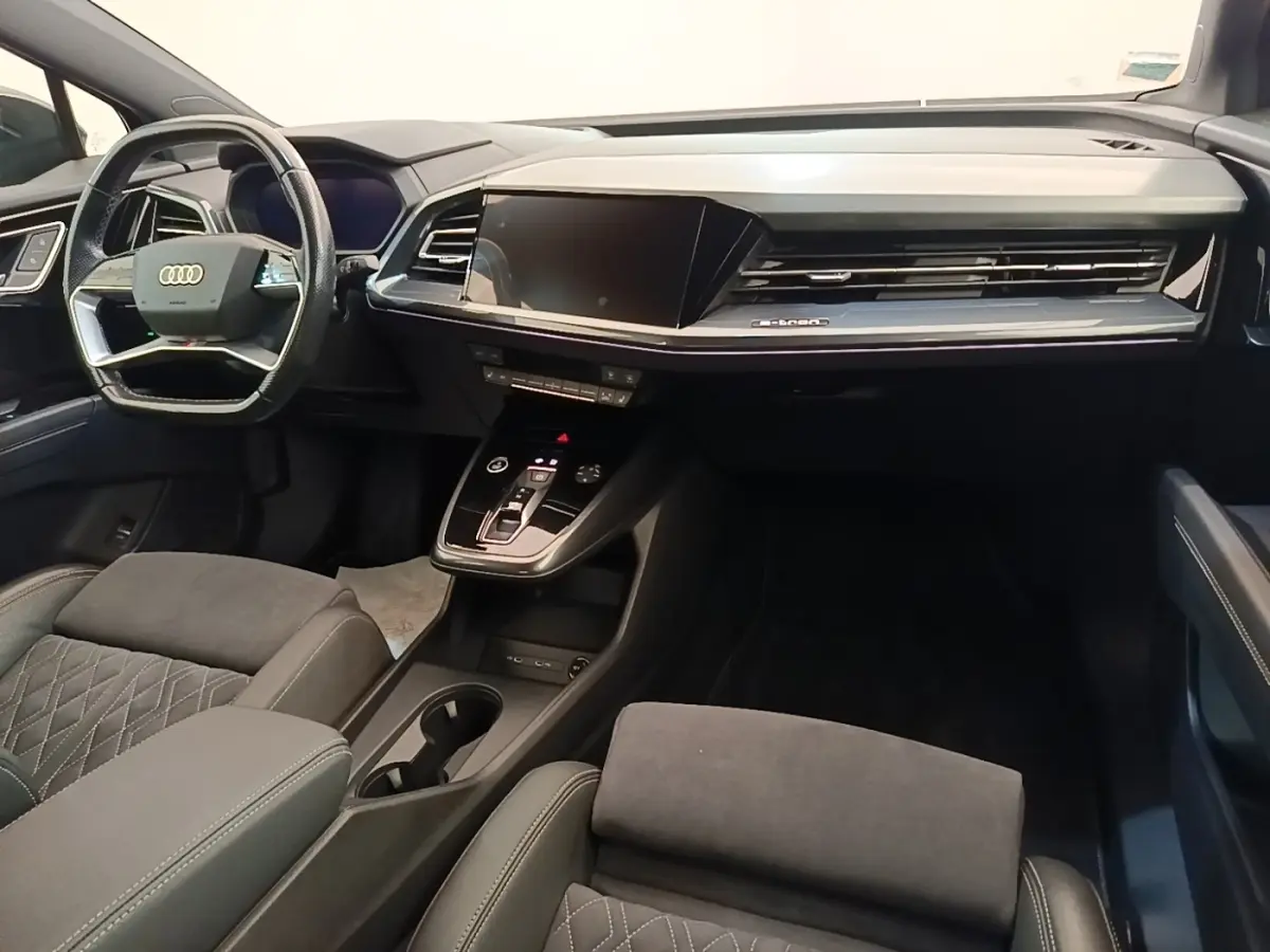 Intérieur noir de l'Audi Q4 E-TRON Sportback 2023, vue du tableau de bord et volant multifonctions côté conducteur.