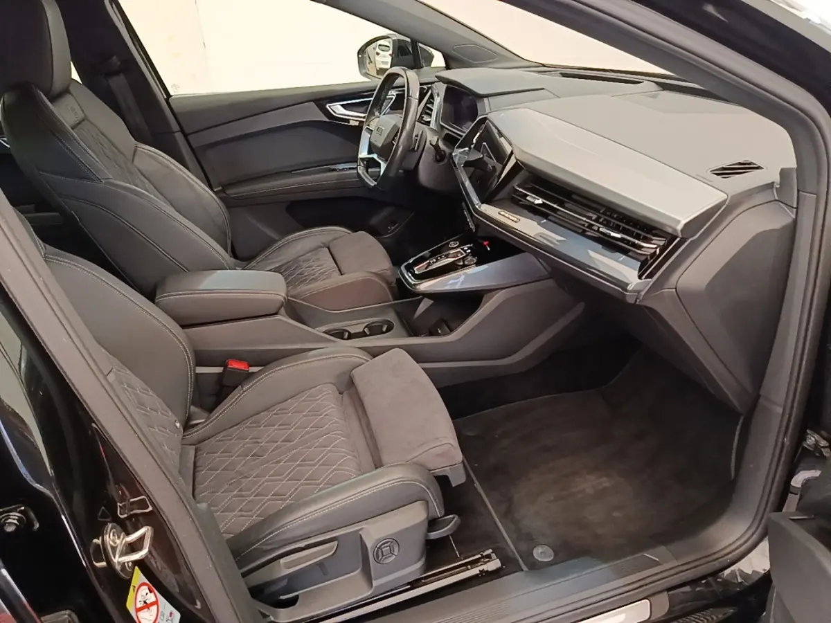Intérieur Audi Q4 E-TRON Sportback noir, vue côté droit montrant sièges en cuir et tableau de bord moderne.