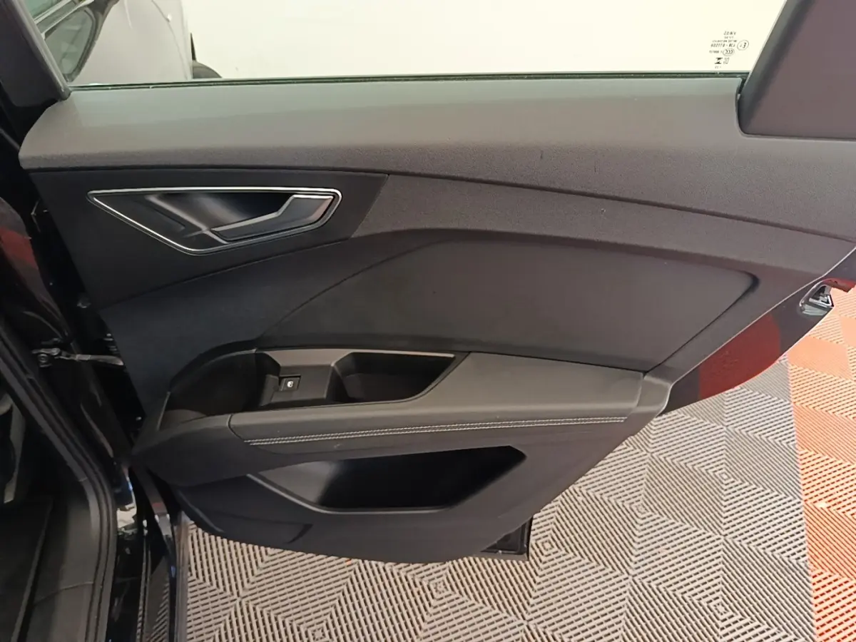 Vue rapprochée de la porte arrière gauche noire de l'Audi Q4 E-Tron Sportback 2023 avec garniture sobre et poignée argentée.