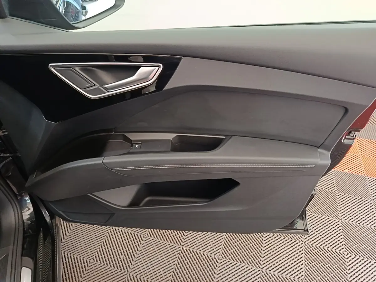 Vue intérieure de la porte avant gauche noire de l'Audi Q4 E-Tron Sportback avec poignée argentée et garniture noire.