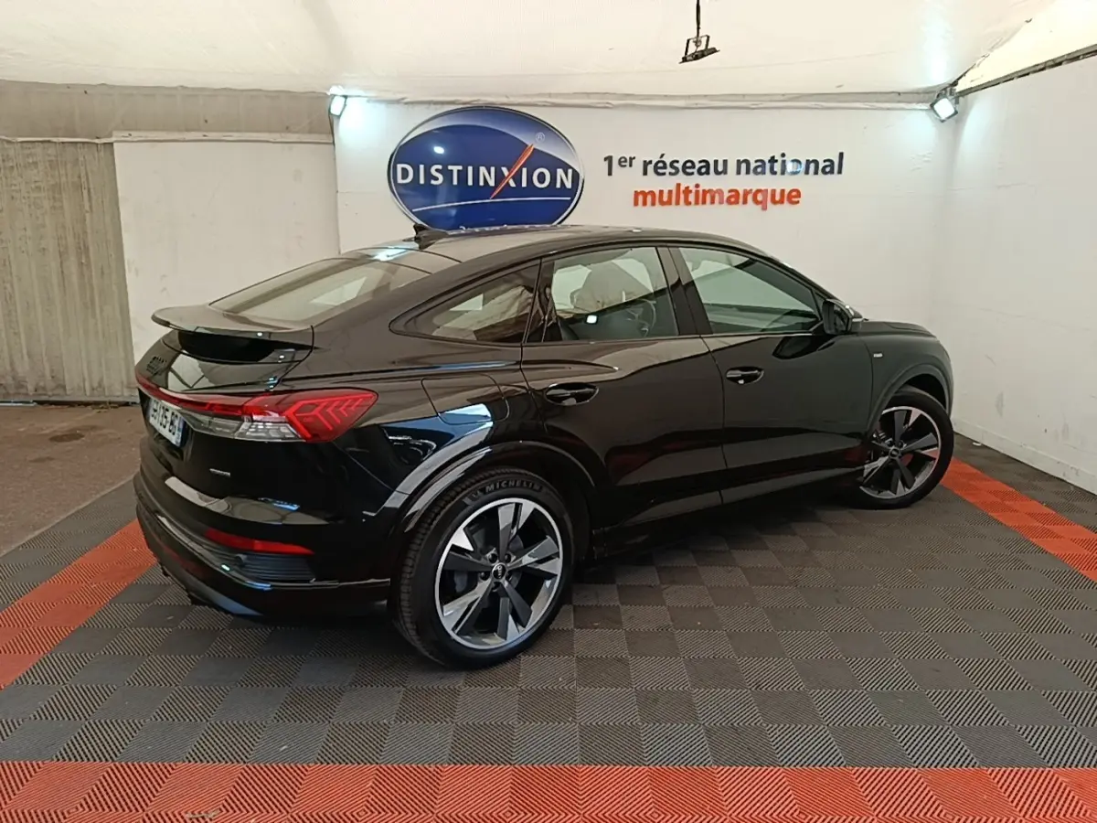Audi Q4 E-Tron Sportback électrique noir, vue 3/4 arrière droit, avec jantes S Line et toit plongeant.