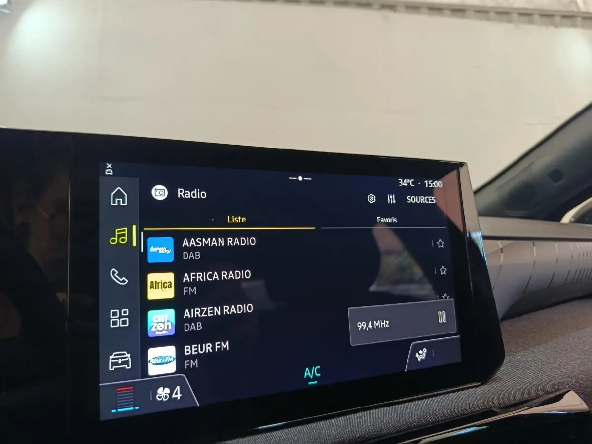 Vue intérieure centrée sur l'écran tactile multimédia de la Renault Clio 2026, affichant la liste des radios.