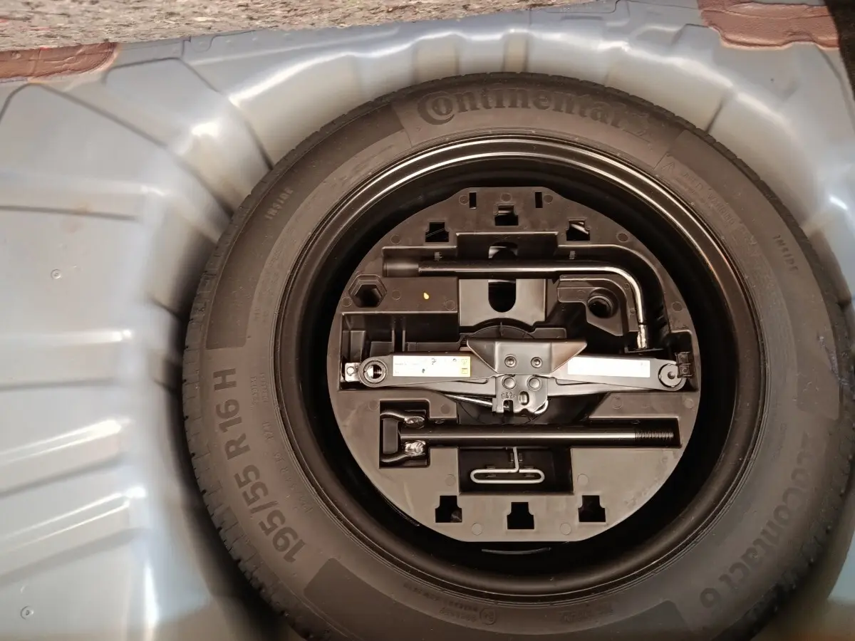 Gros plan sur la roue de secours et son kit d'outils dans le coffre d'une Renault Clio bleu 2026.