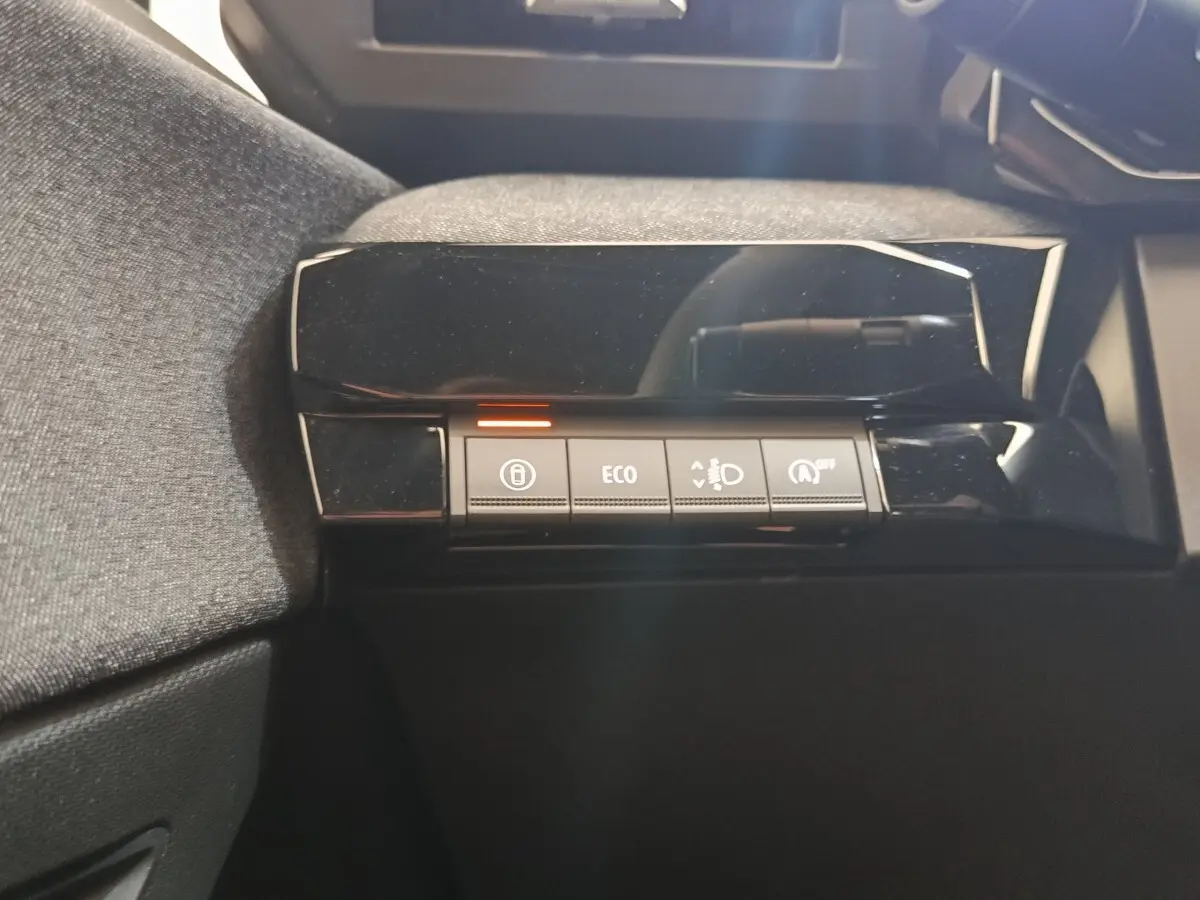 Gros plan sur les boutons de commande du tableau de bord noir brillant de la Renault Clio bleu, version 2026.