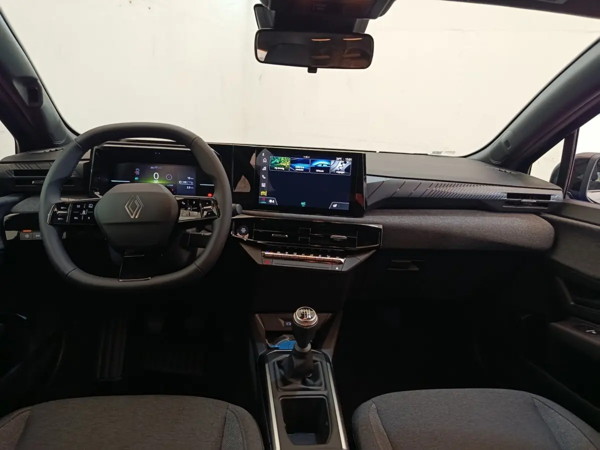 Vue intérieure avant de la Renault Clio bleu, volant multifonctions, écran tactile central et boîte manuelle visible.