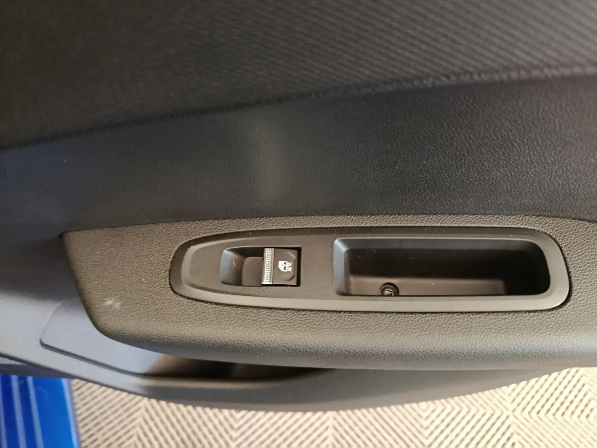 Détail de la commande de verrouillage des portes sur la portière côté gauche d'une Renault Clio bleue.