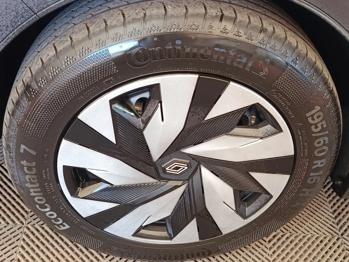 Gros plan sur la roue avant droite de la Renault Clio bleu, avec jante au design géométrique noir et argent.