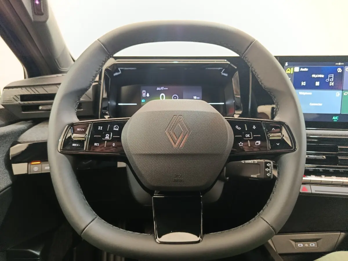 Vue rapprochée du volant multifonctions noir de la Renault Clio 2026 avec tableau de bord digital et écran central.