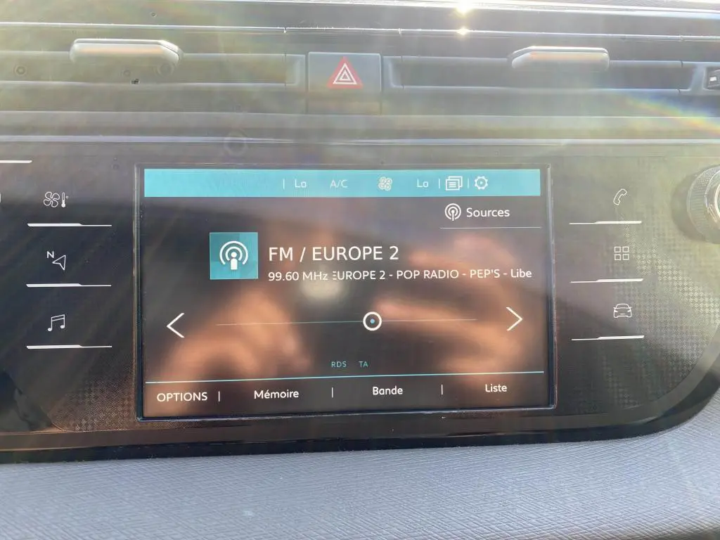 Écran tactile central de la Citroën C4 Spacetourer blanc, affichant la radio FM Europe 2 en plein jour.