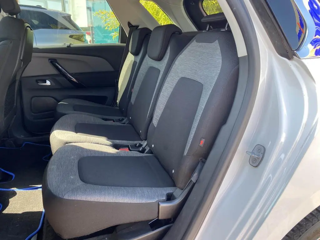 Vue latérale intérieure sur les sièges arrière gris et noirs du Citroën C4 Spacetourer blanc, porte arrière ouverte.