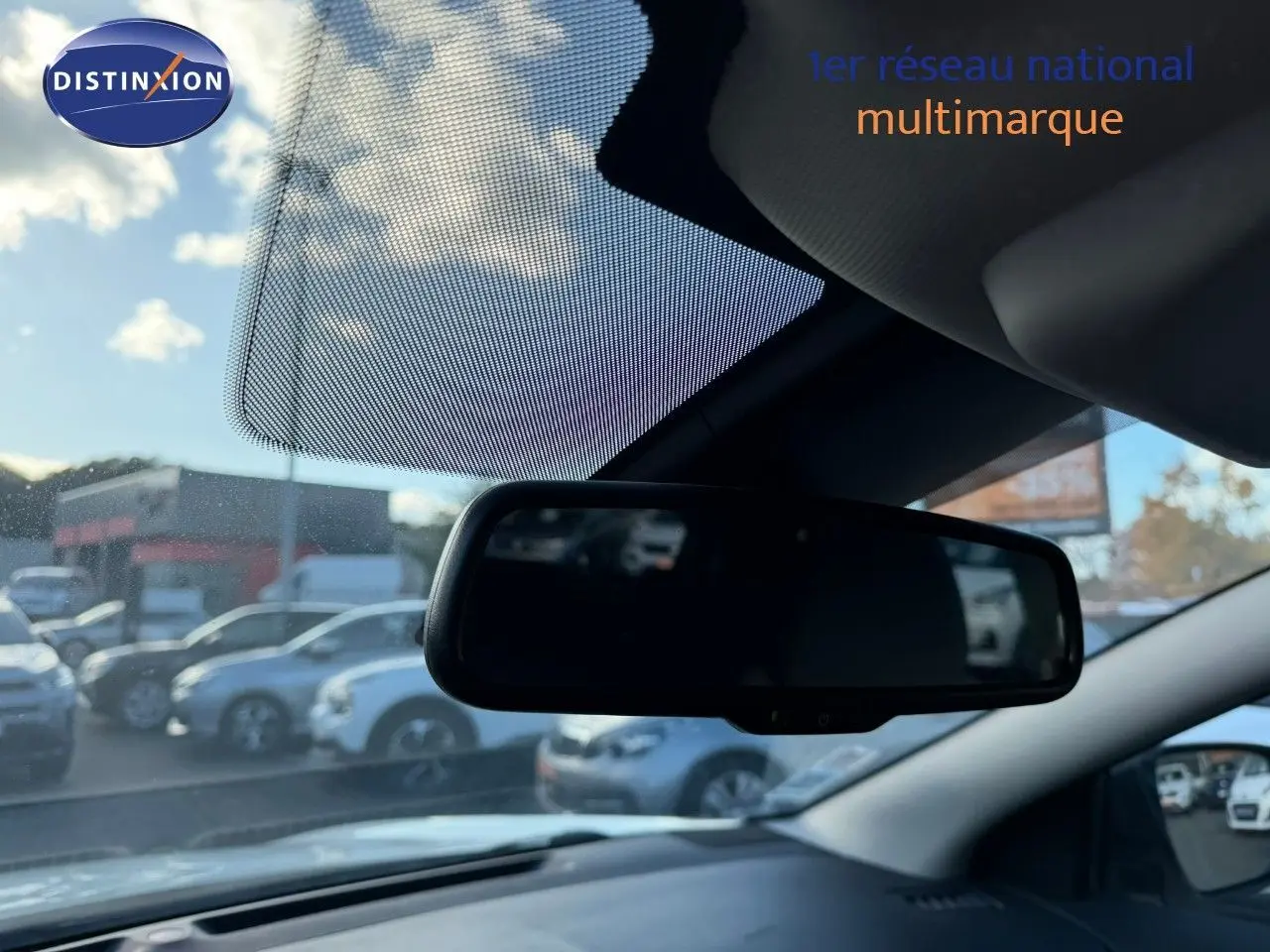 Rétroviseur intérieur du Nissan Qashqai blanc nacré, vue depuis l’habitacle avec ciel et voitures en arrière-plan flous.