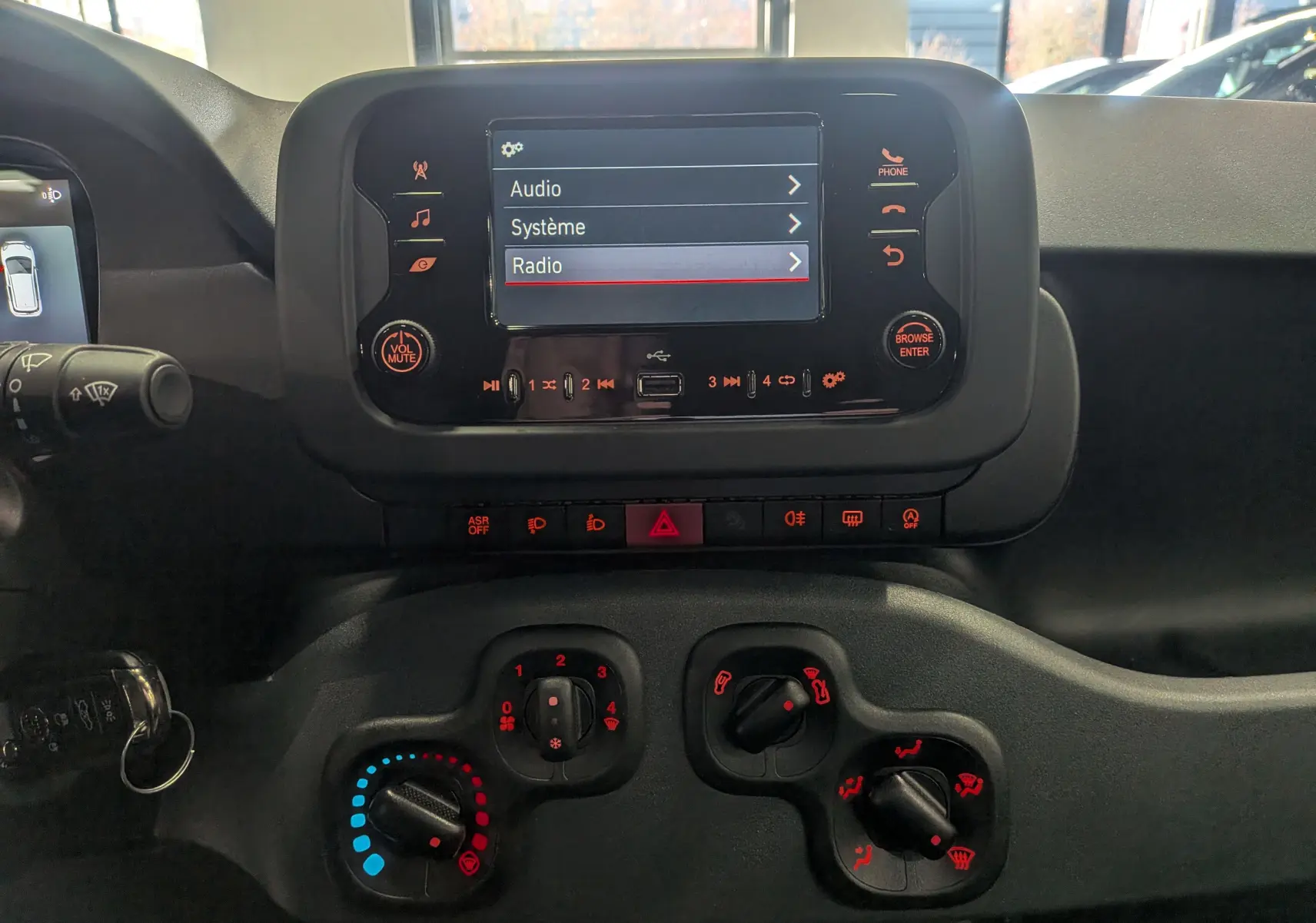 Vue rapprochée du tableau de bord de la Fiat Panda Bleu Italia 2025, avec écran tactile et commandes manuelles de climatisation.