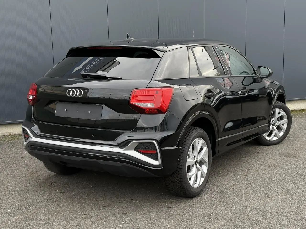 Audi Q2 noir Mythe vue 3/4 arrière droit, hayon électrique et feux arrière LED distinctifs visibles.