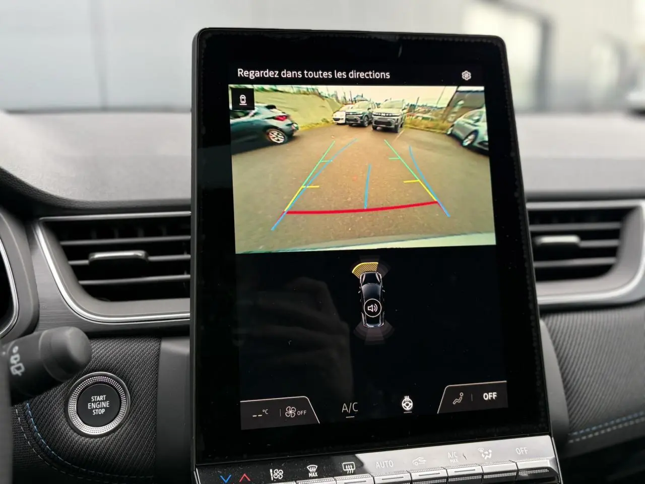 Écran central tactile du Renault Captur 2025 affichant la caméra de recul avec aides au stationnement, intérieur gris et coutures bleues.