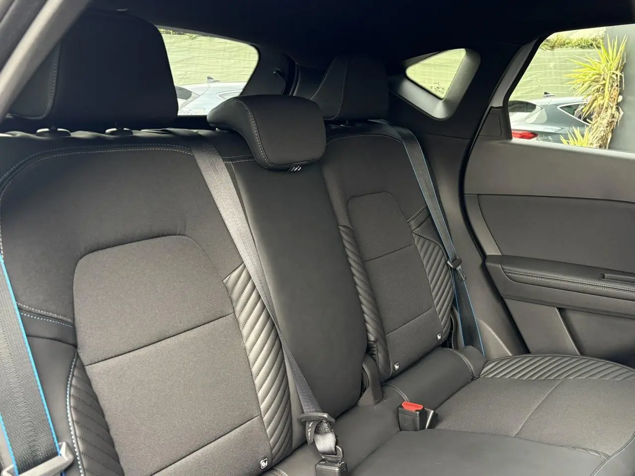 Vue intérieure côté droit de la banquette arrière noire avec surpiqûres bleues du Renault Captur Esprit Alpine 2025.