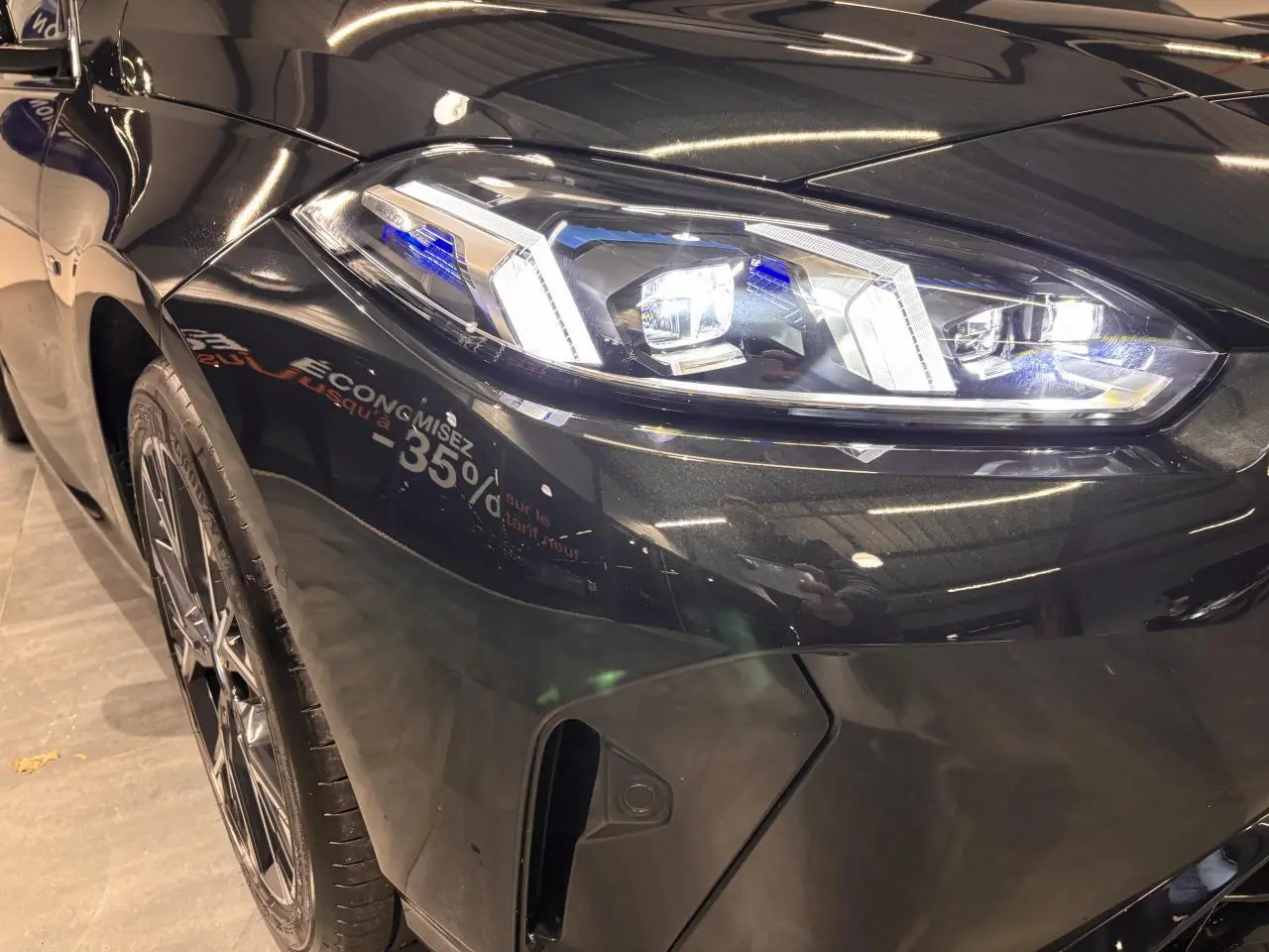 Gros plan sur l'avant droit noir métal de la BMW Série 1 118d M Sport avec phares LED allumés et jante alliage 18 pouces.