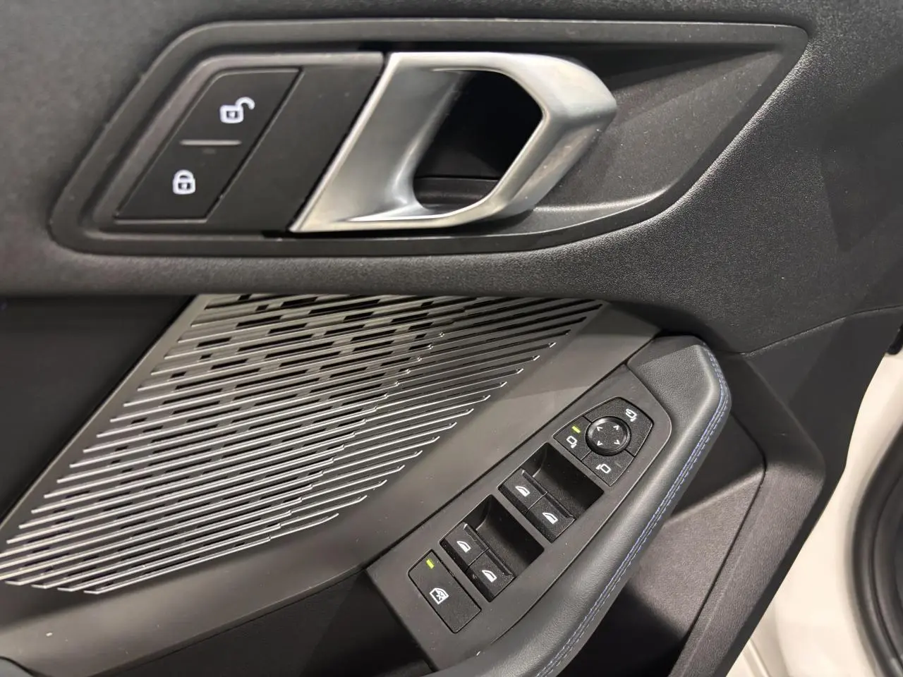 Détail de la porte avant gauche noire de la BMW Série 1 118d M Sport 2025 avec commandes de vitres et haut-parleur intégré.