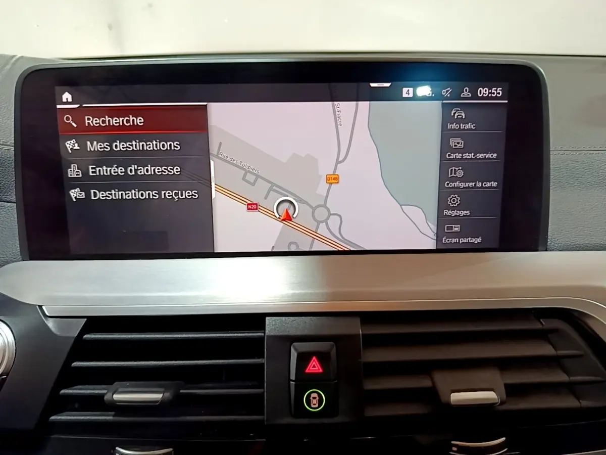 Vue intérieure du tableau de bord de la BMW X3 noir, écran tactile de navigation affichant une carte en mode recherche.