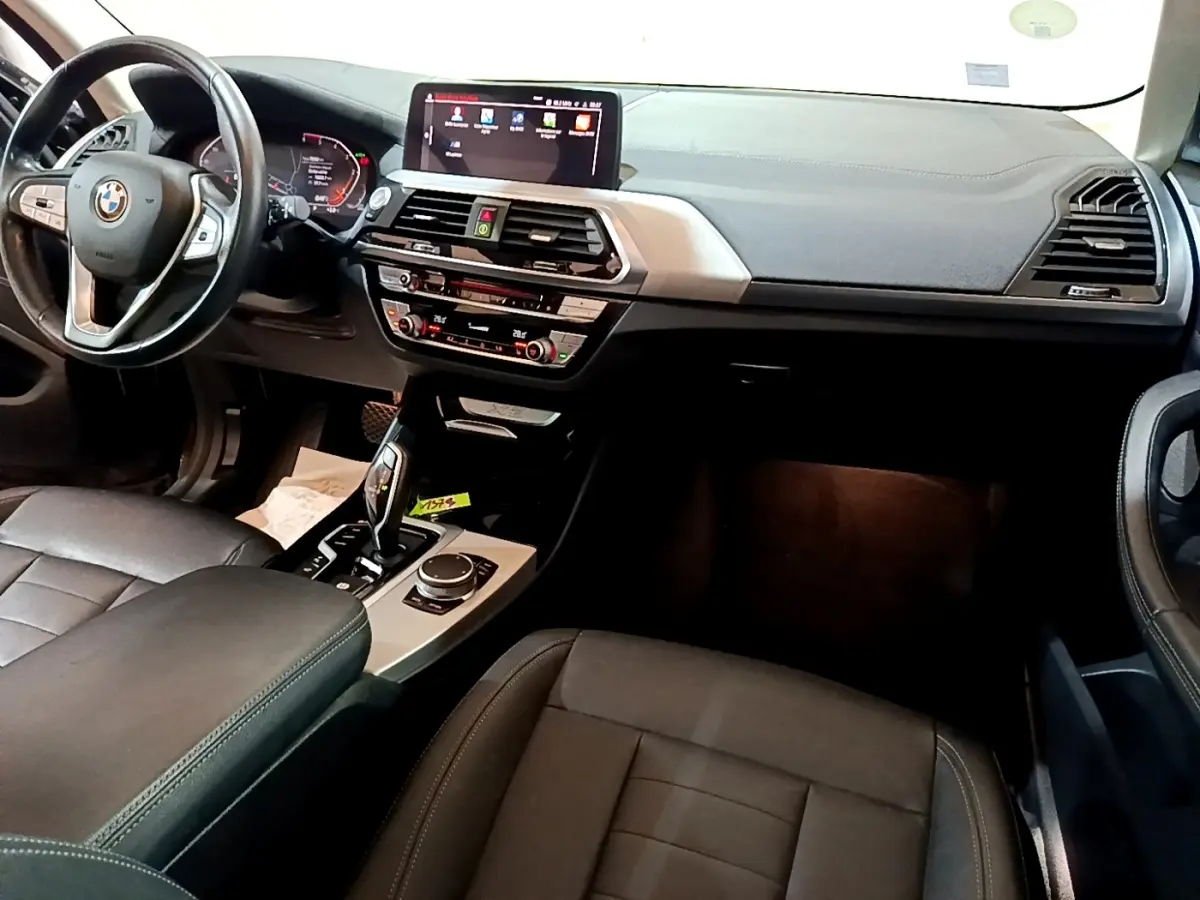 Intérieur noir de BMW X3 2019 vu de face, avec tableau de bord digital et console centrale tactile.