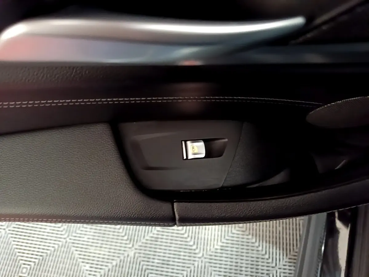 Détail de la commande de condamnation centralisée sur la porte intérieure côté conducteur d’un BMW X3 noir.