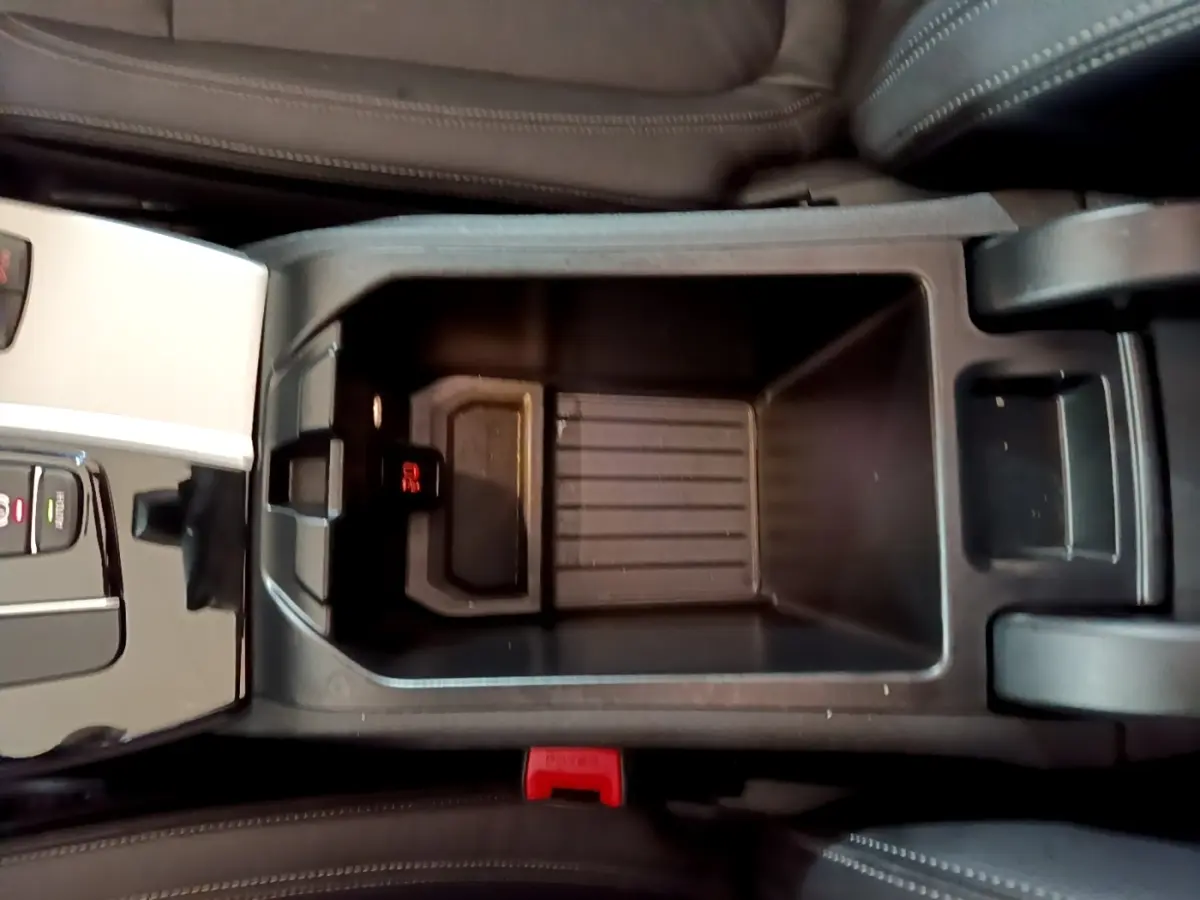 Vue plongeante sur le rangement central noir entre les sièges en cuir marron du BMW X3 sDrive18d 2019.