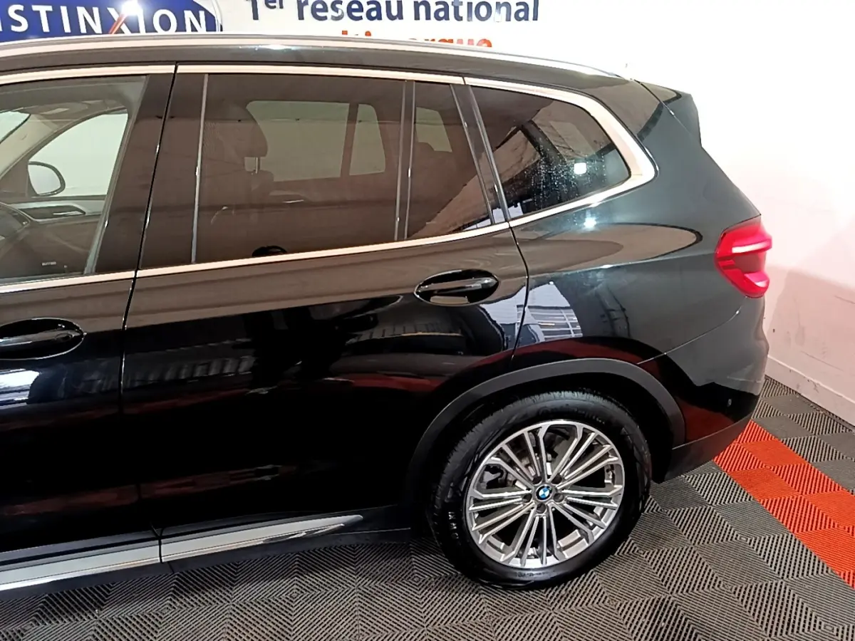 Vue latérale droite sur l’arrière d’un BMW X3 noir 2019 avec jante alliage et feux arrière LED allumés.