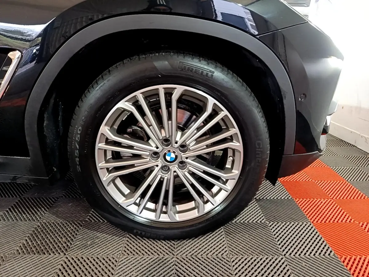 Gros plan sur la roue avant droite d’un BMW X3 noir, mettant en valeur la jante alliage multi-branches et le pneu Pirelli.