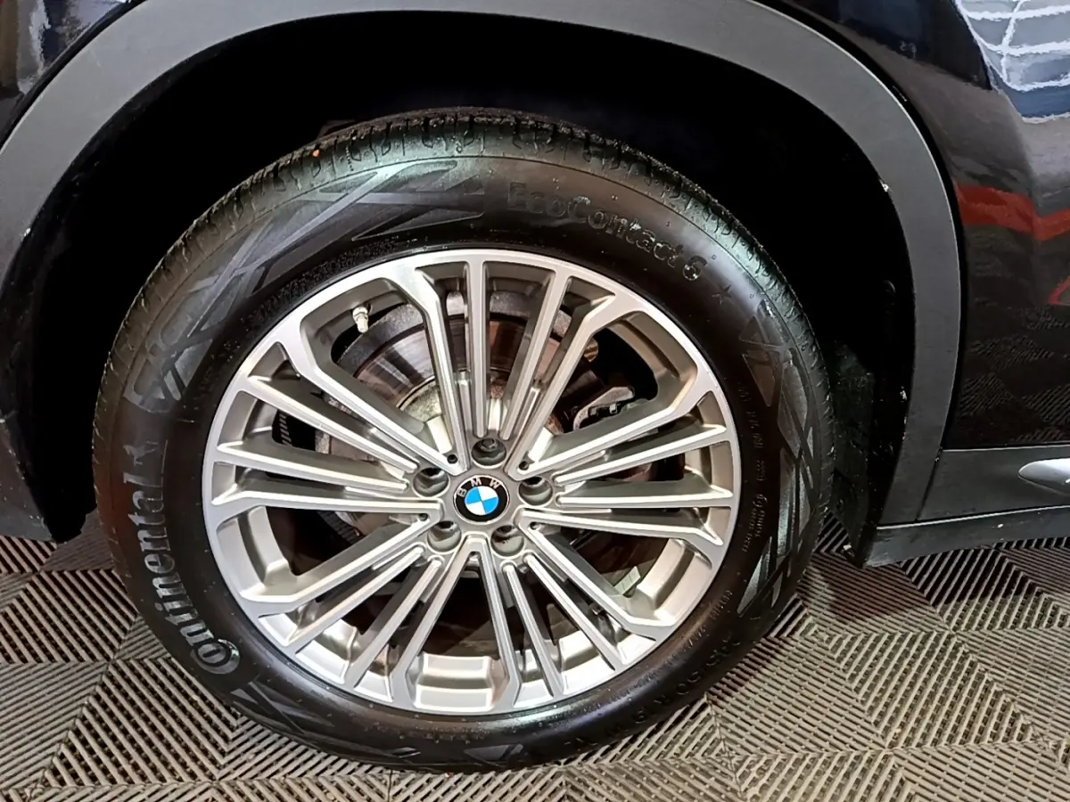 Gros plan sur la roue avant droite d’un BMW X3 noir, mettant en valeur la jante alliage multi-branches et le pneu Continental.