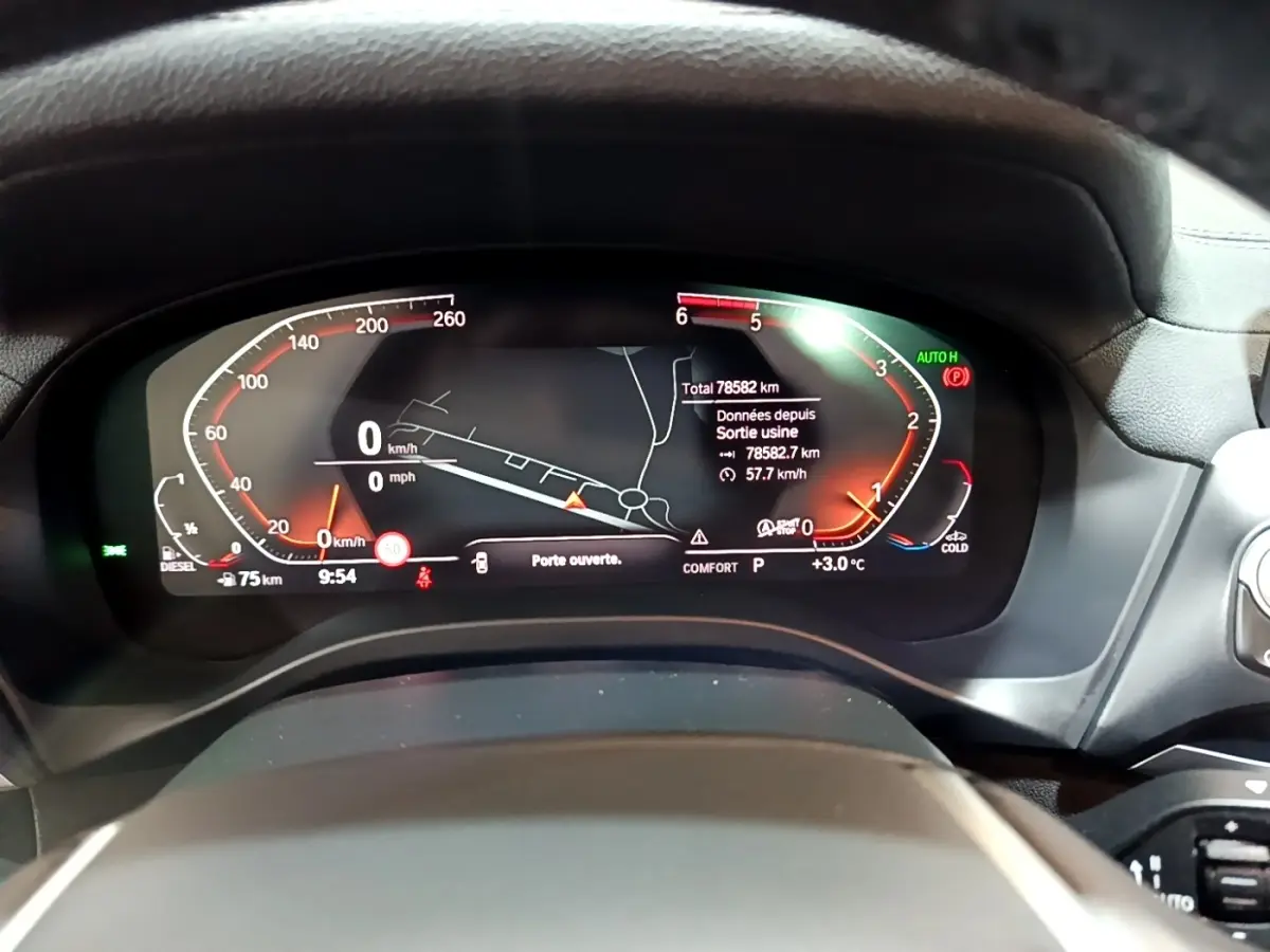 Vue rapprochée du tableau de bord numérique du BMW X3 noir, affichant la navigation et les indicateurs de vitesse.
