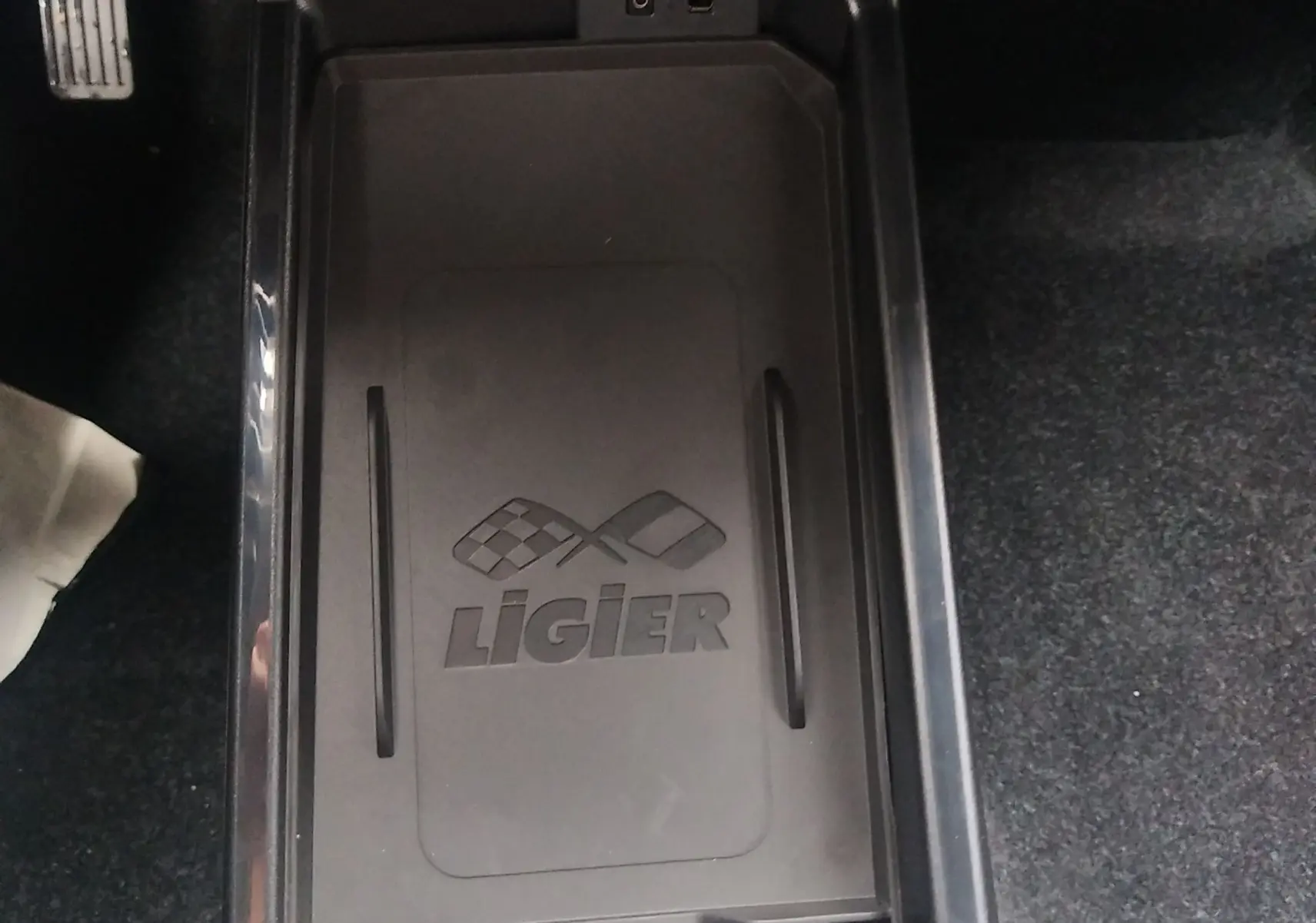 Vue plongeante sur la console centrale noire du Ligier JS50 REVO D+ Select avec logo et ports USB visibles.
