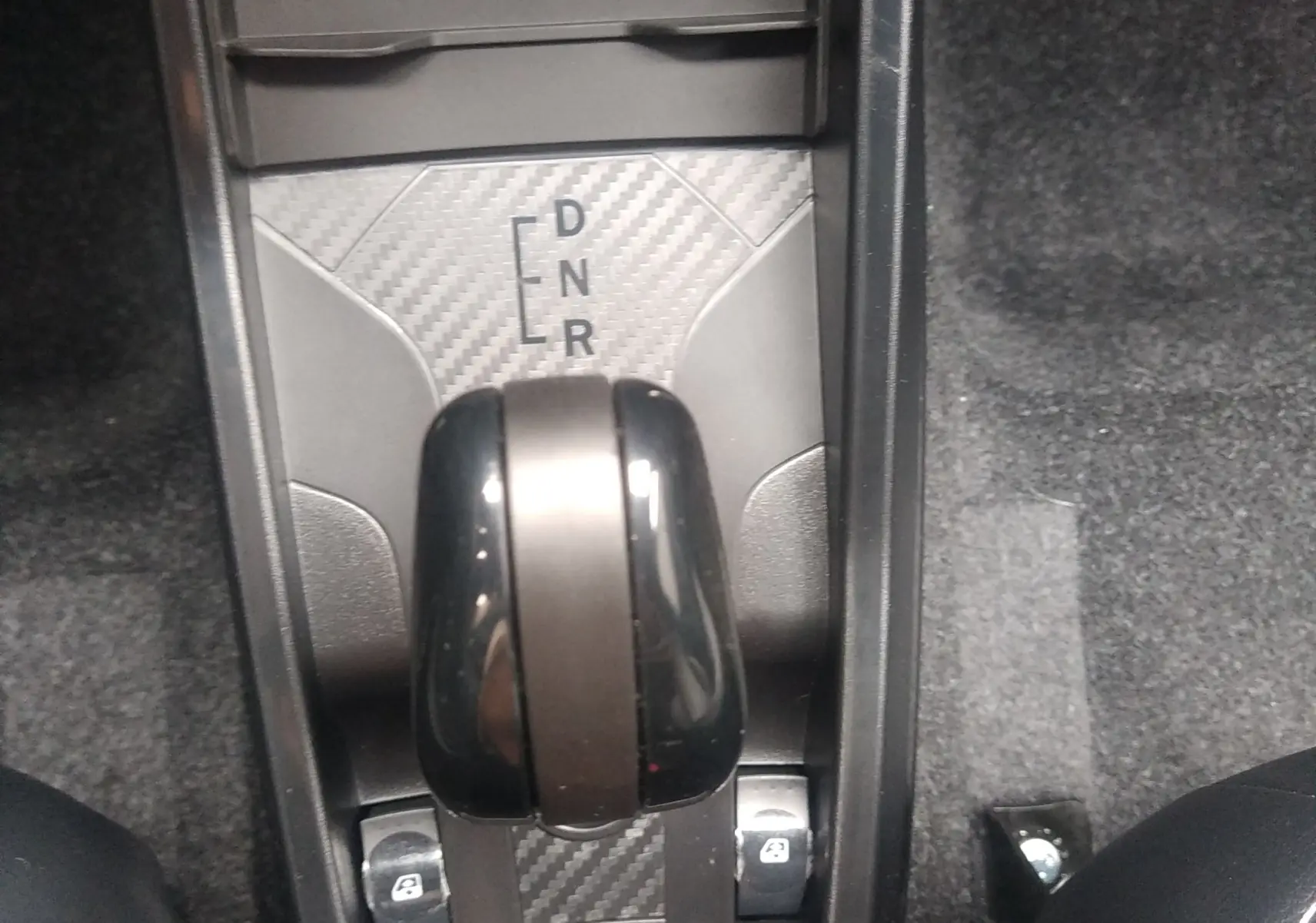 Gros plan sur la console centrale de la Ligier JS50 REVO D+ Select 2026, levier de boîte auto noir avec insert carbone.