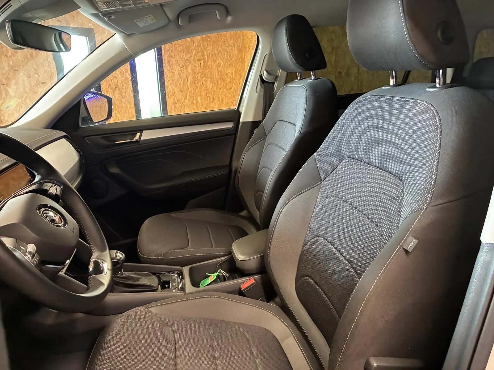 Vue intérieure côté conducteur du Skoda Kodiaq gris clair 2023, sièges tissu noir et tableau de bord moderne.