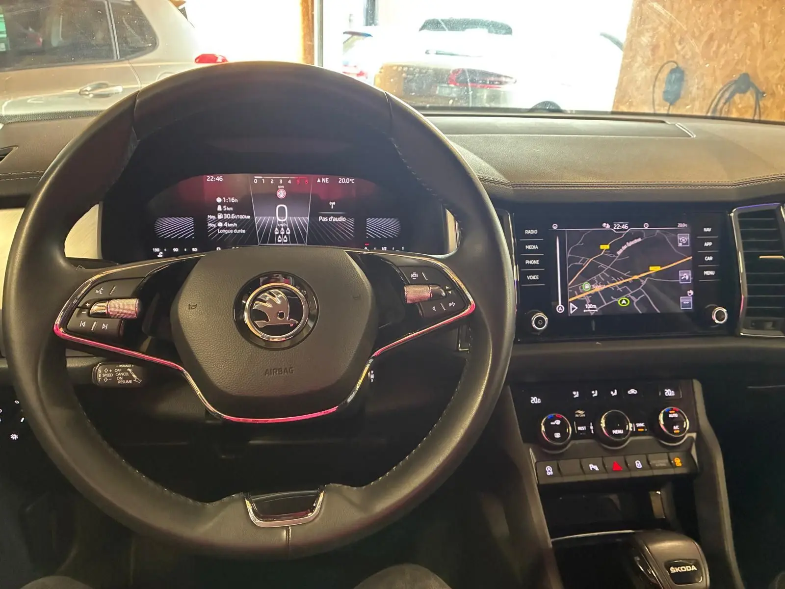 Vue intérieure centrée sur le volant noir et le tableau de bord numérique du Skoda Kodiaq gris clair 2023 avec écran GPS tactile.