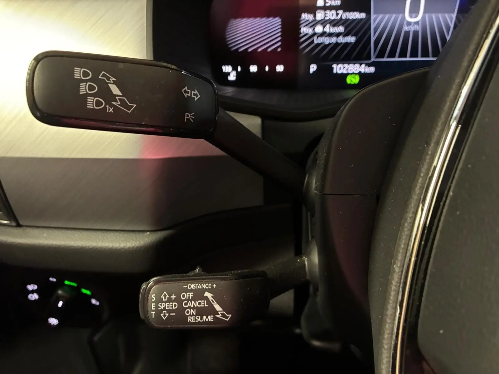 Gros plan sur les commandes au volant du Skoda Kodiaq gris clair 2023, avec affichage digital en arrière-plan.
