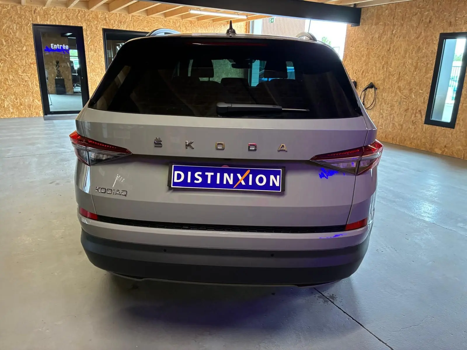 Vue arrière d'un Skoda Kodiaq gris clair 2023 avec feux arrière LED et plaque Distinxion dans un garage.