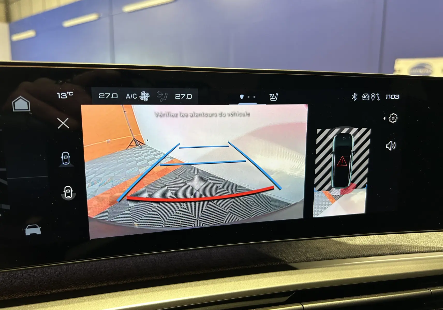 Vue caméra 360° montrant un SUV Peugeot 3008 bleu en stationnement intérieur avec lignes d’aide au recul.