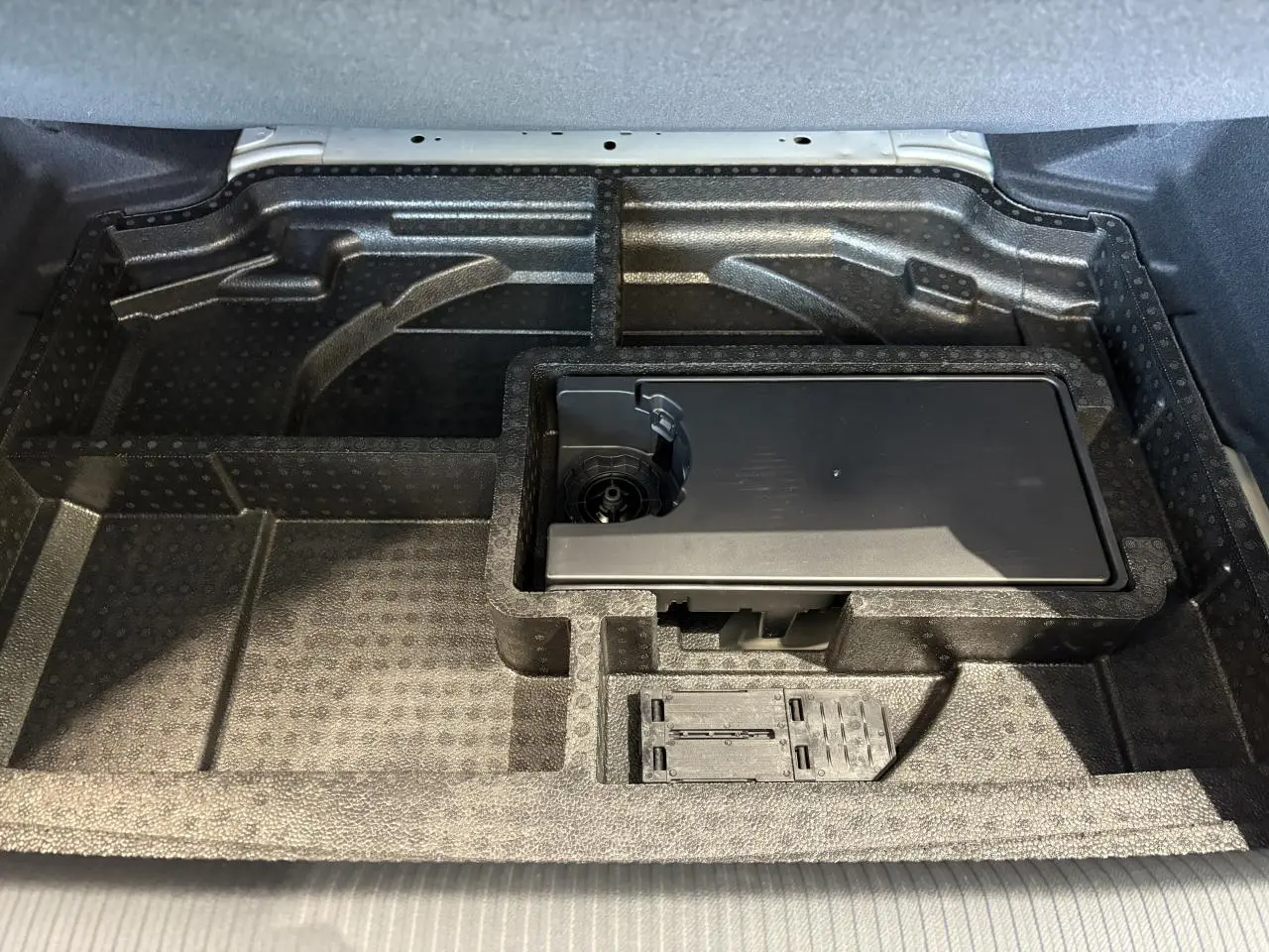 Compartiment de rangement sous le coffre de la Peugeot 308 gris Selenium, avec kit de dépannage pneumatique intégré.