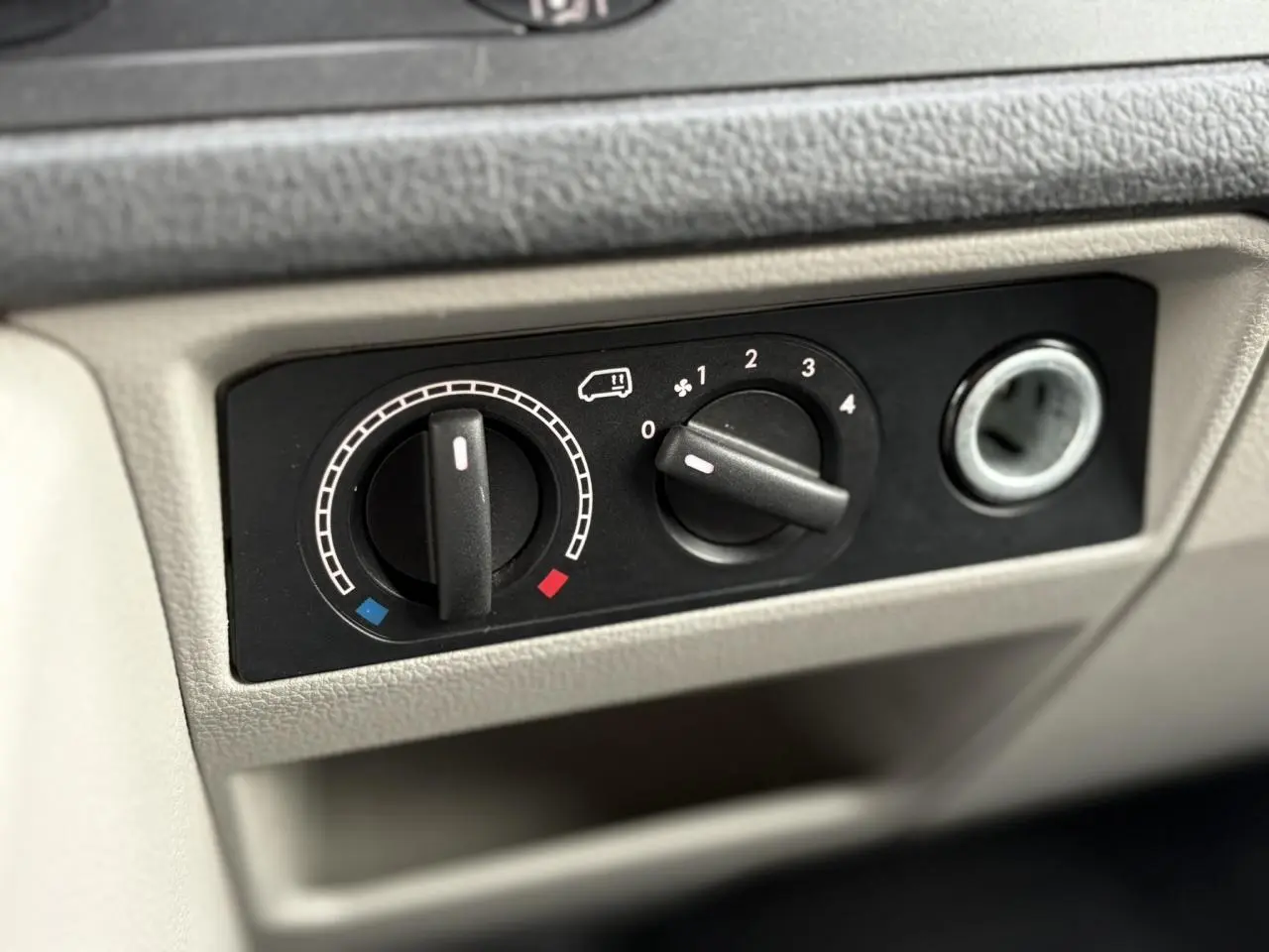 Gros plan sur les commandes de chauffage et ventilation du tableau de bord beige du Volkswagen Transporter 2017 jaune et blanc.