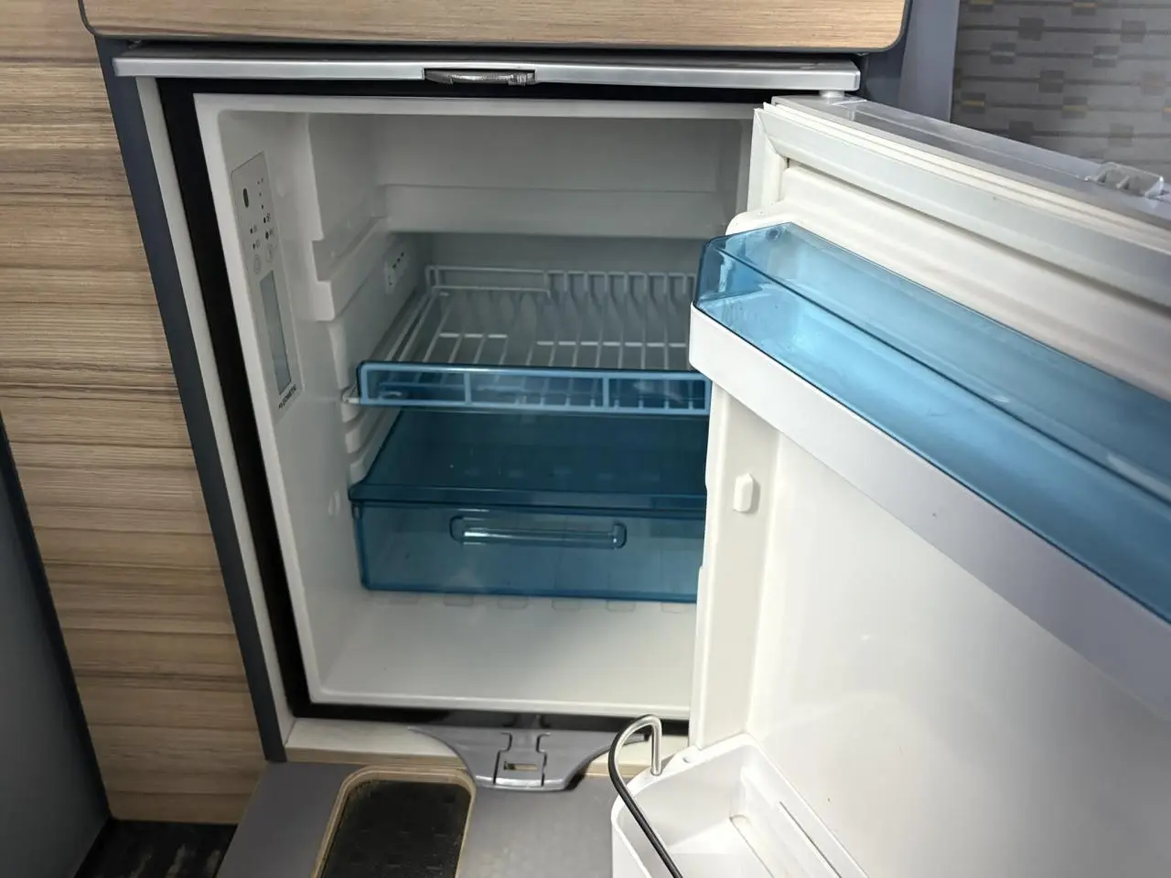 Gros plan sur le frigo ouvert intégré dans l'aménagement intérieur du Volkswagen Transporter jaune et blanc 2017.