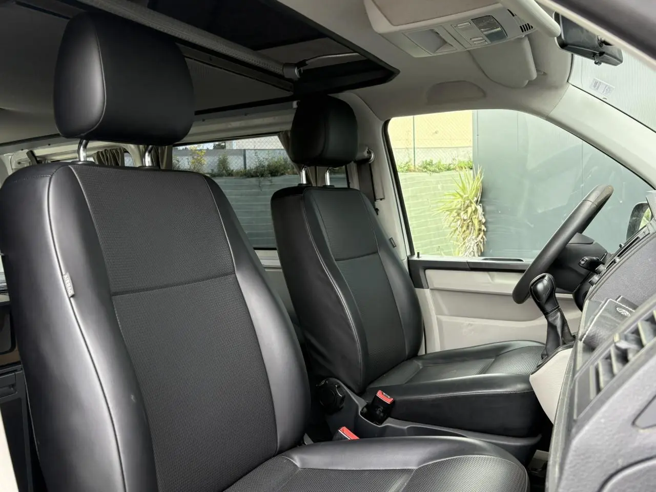 Intérieur du Volkswagen Transporter 2017, vue côté conducteur, sièges confort pivotants en cuir noir.