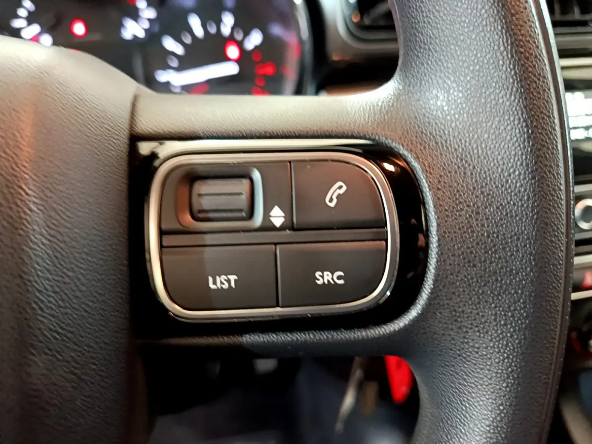 Gros plan sur les commandes multifonctions du volant noir d'une Citroën C3 blanche PureTech 68 BVM Feel 2018.