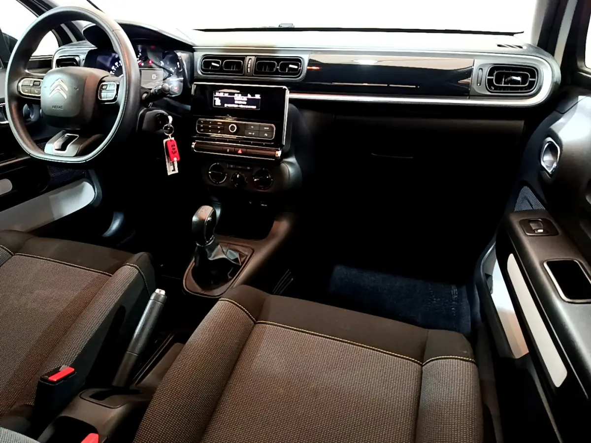 Intérieur avant droit de Citroën C3 blanc 2018, tableau de bord noir avec écran central et boîte manuelle visible.